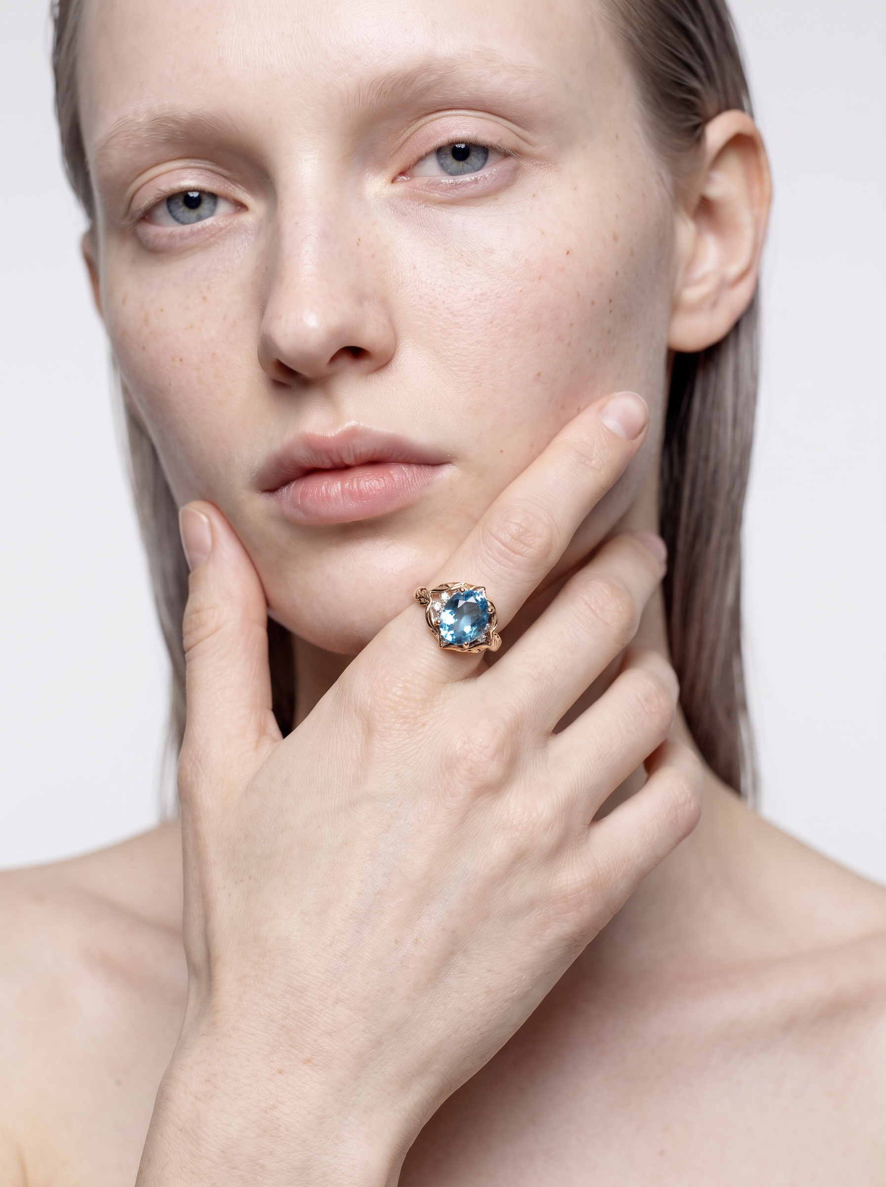 Model wearing the Sea Leaf blue topaz leaf ring, hand at the chin