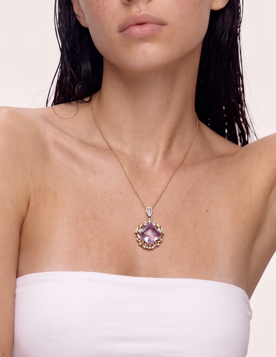 Lilac amethyst pendant with gold leaf frame worn at the neckline, arm raised to the head