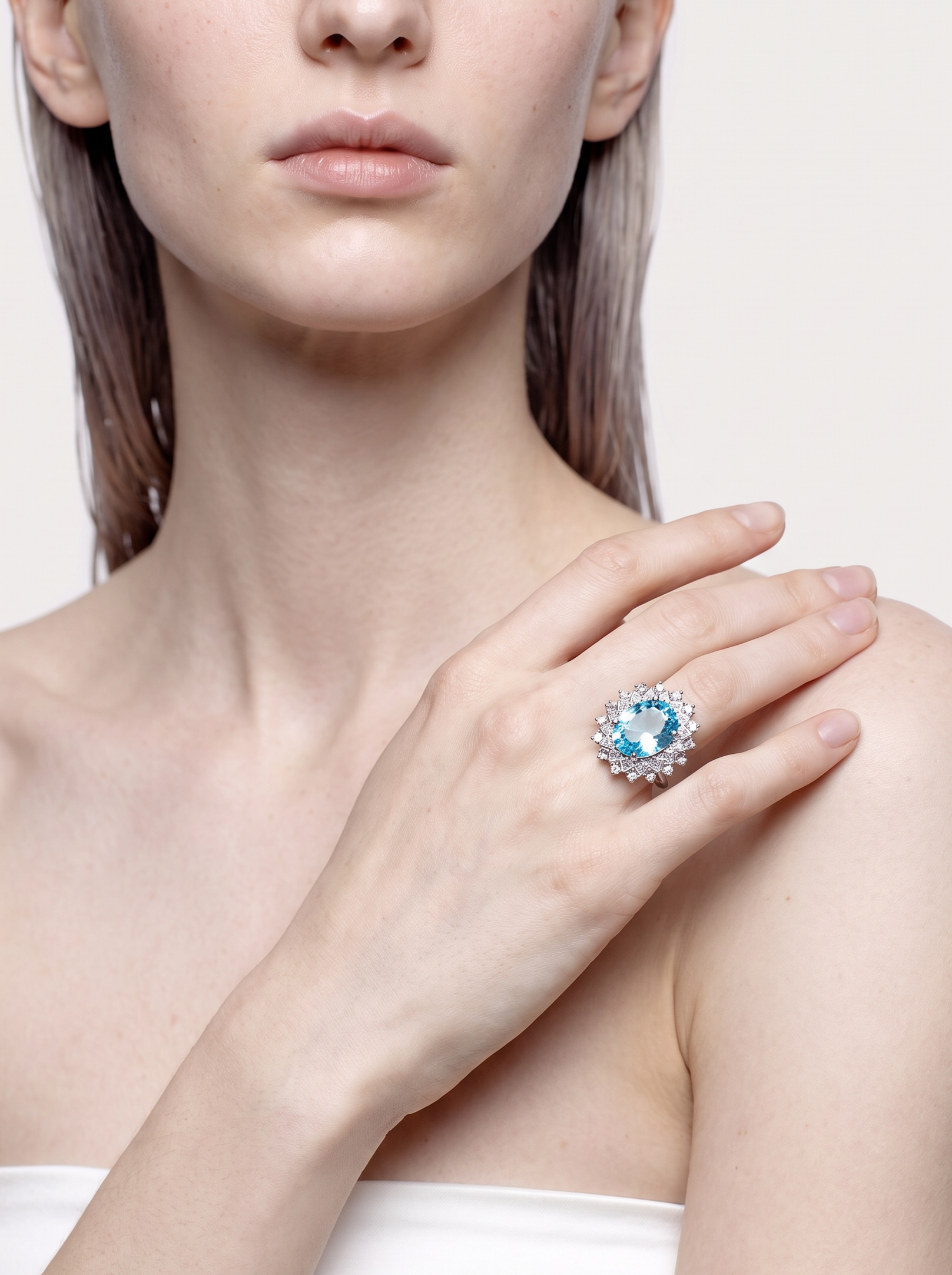 Model wearing the Ice Lagoon blue topaz ring, hand at the collarbone