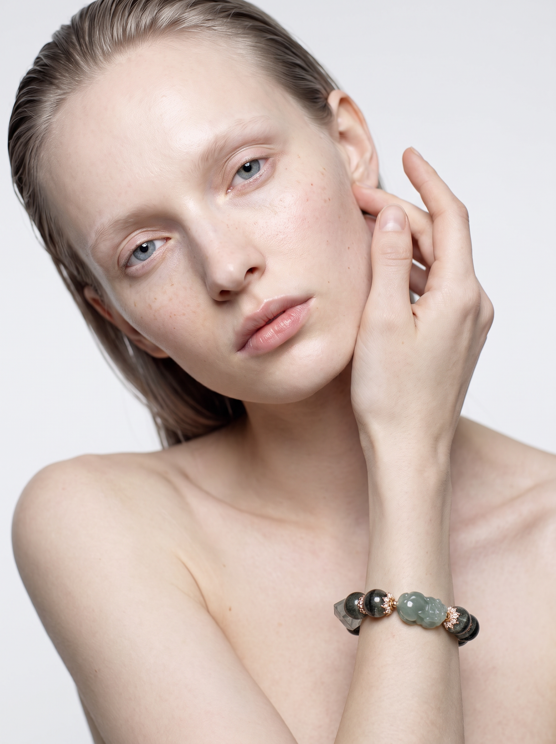 Model wearing the Kelp Guardian green phantom quartz pixiu bracelet on the wrist, hand raised to the face