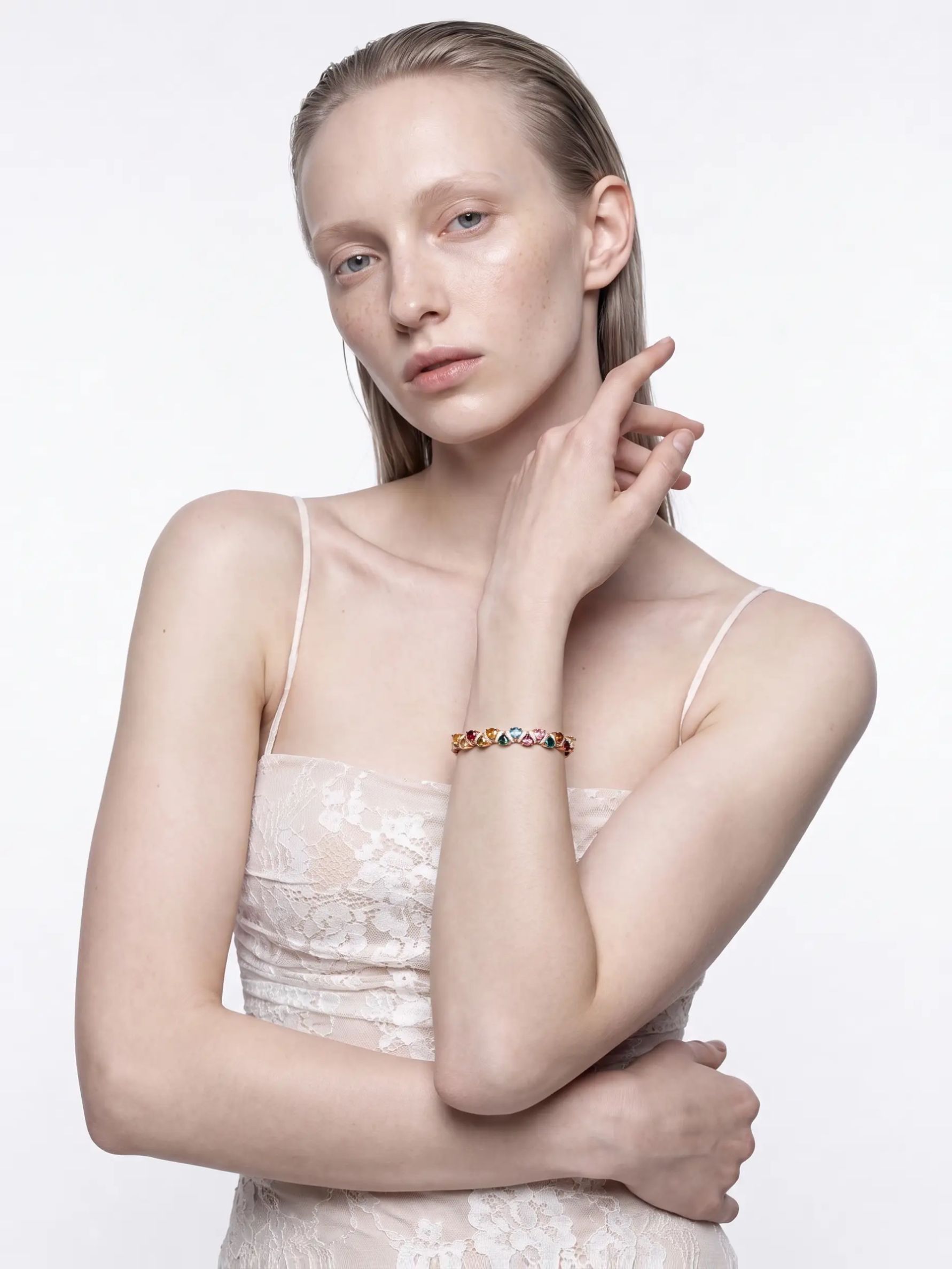 Multicolour tourmaline rose gold bangle worn on the wrist, arm across the body