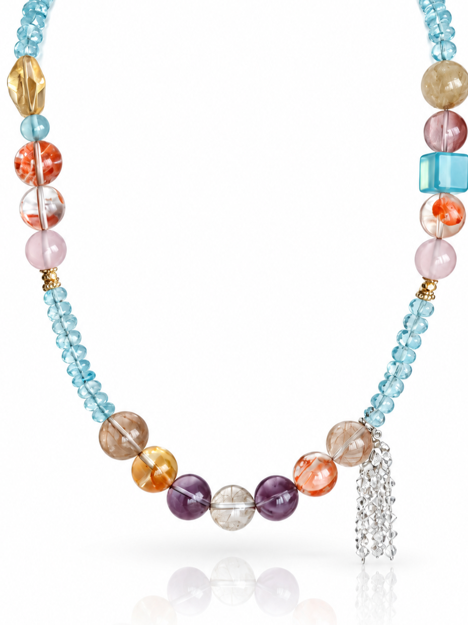 Close-up of blue topaz rondelles, aquamarine square bead and clear quartz chip tassel on the Coral Cascade necklace