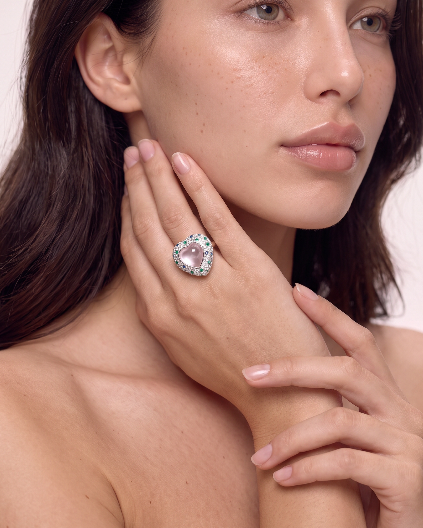 Model wearing the rose quartz heart ring, hand raised to the face