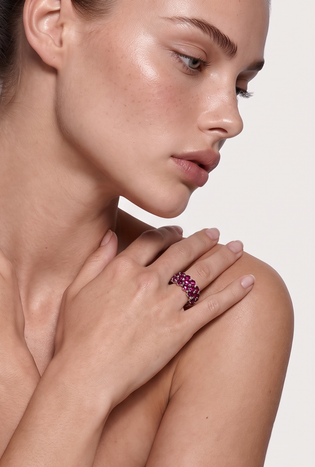 Garnet three-row band ring worn on the finger, hands resting on the shoulders