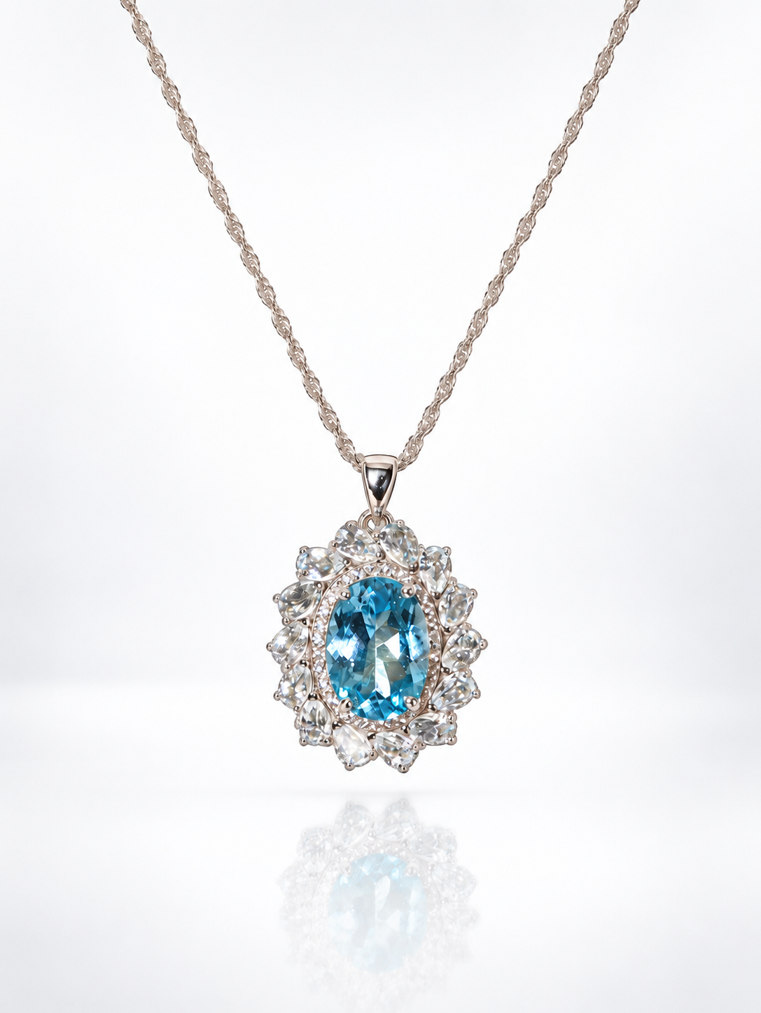 Blue topaz oval pendant surrounded by pear-cut aquamarine petals and cubic zirconia on a rope chain, white background