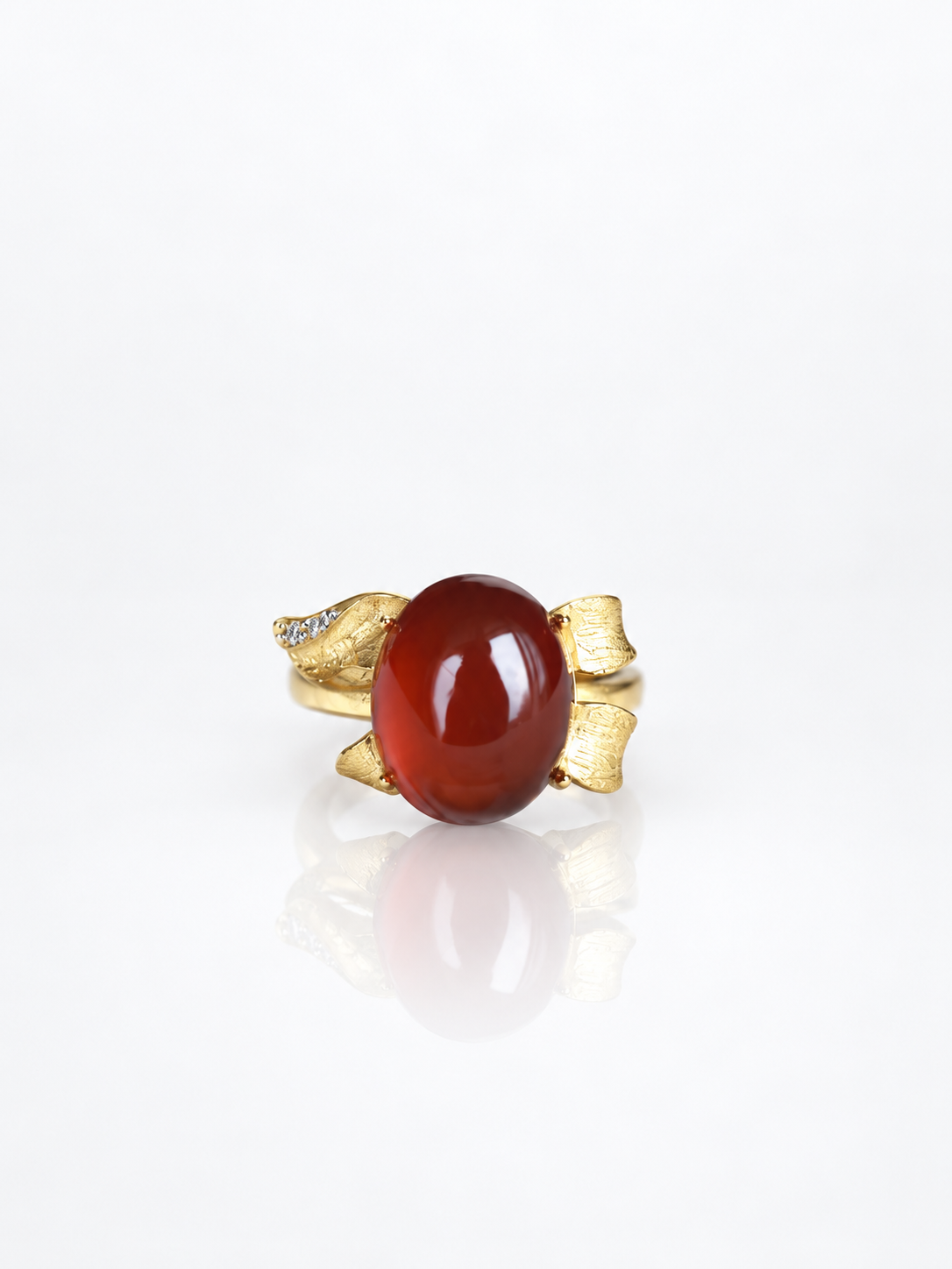 Red garnet cabochon ring with a sculpted gold bow design