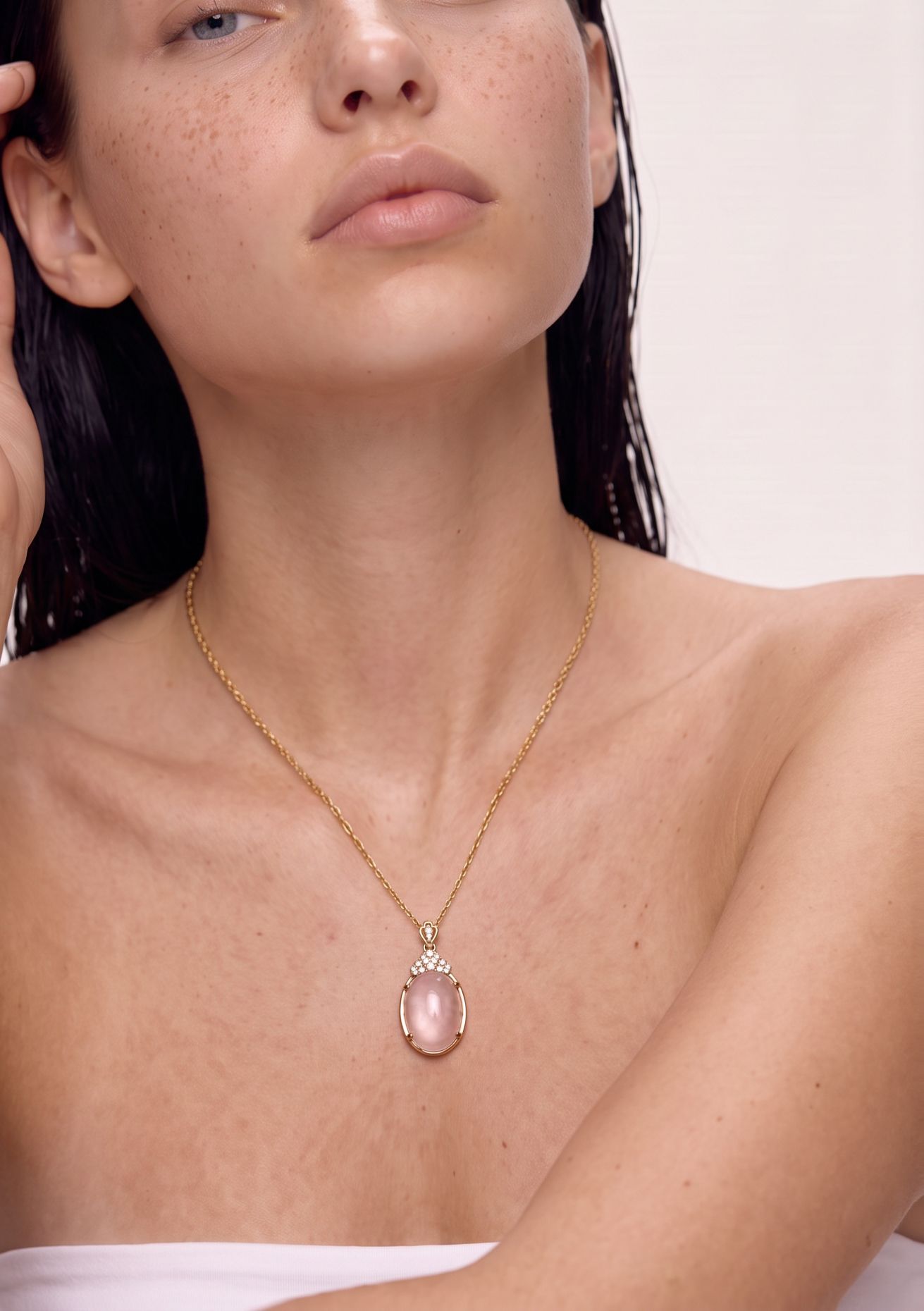 Model wearing the Starlit Blush star rose quartz pendant necklace in gold, hand raised to the hair