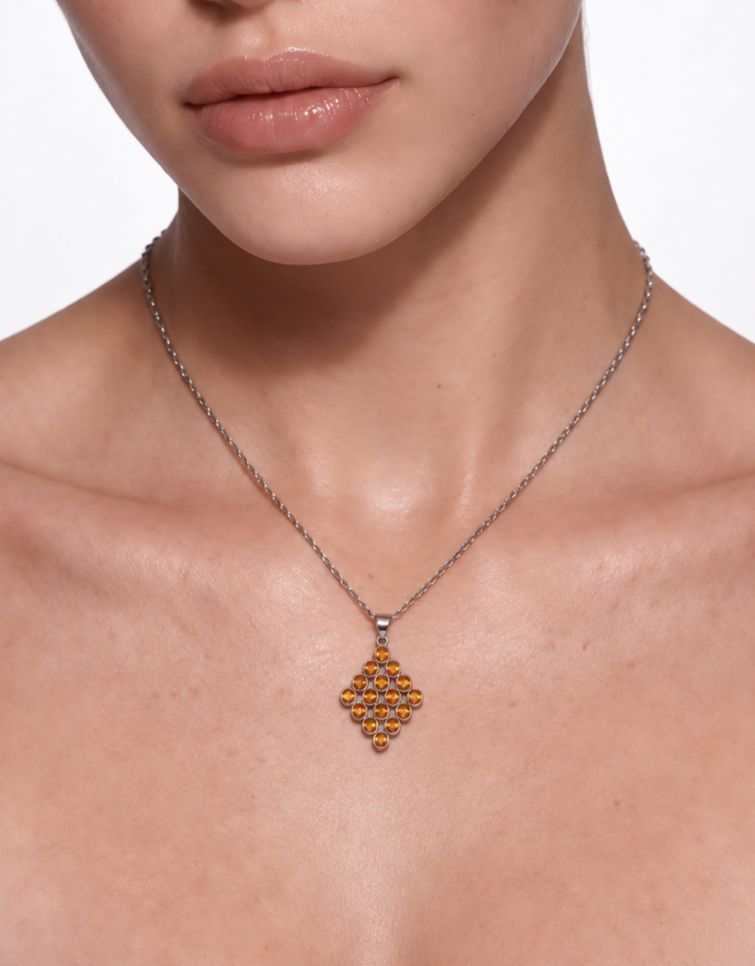 Close-up of the citrine lattice pendant worn at the neckline