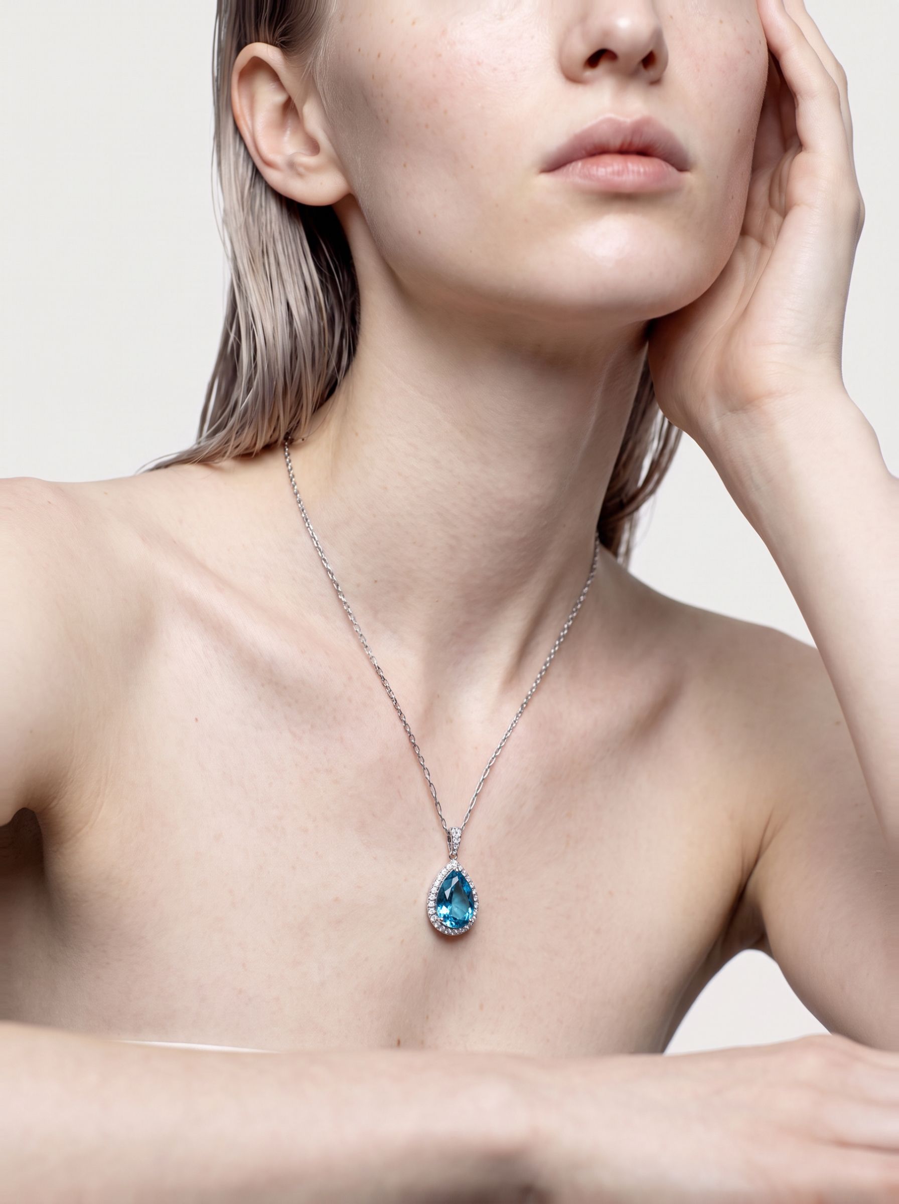 Deep blue pear-shaped topaz pendant in sterling silver worn at the neckline