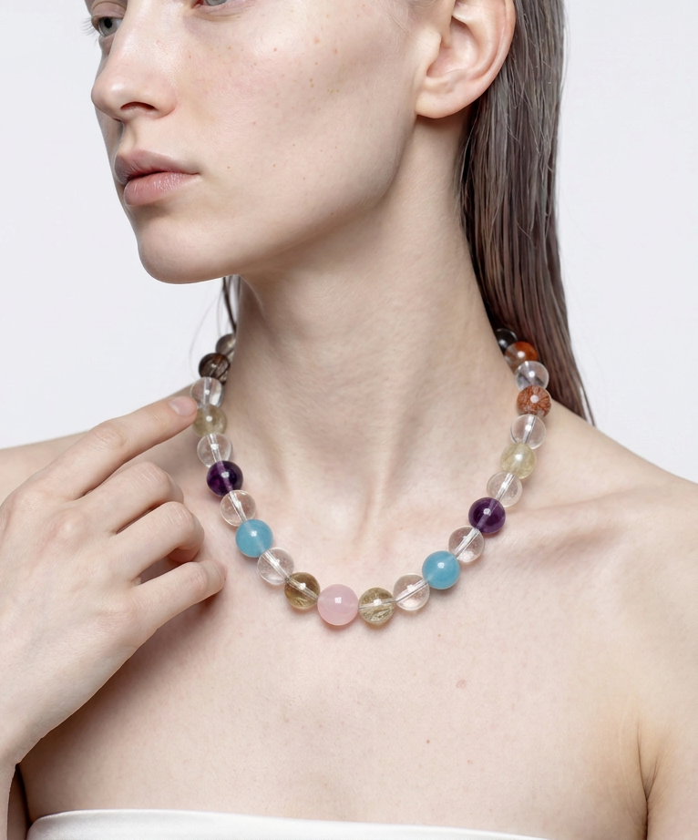 Multi-crystal beaded necklace worn at the neckline, hand resting at the collarbone