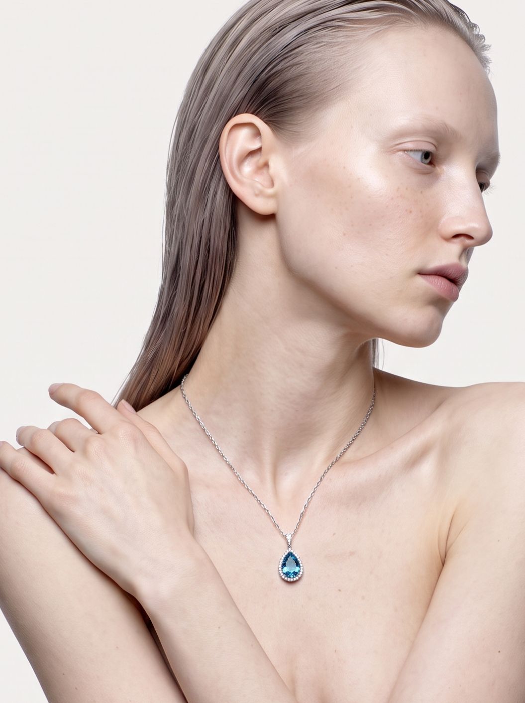 Model wearing the Deep Current London blue topaz pendant necklace, hand resting on the shoulder