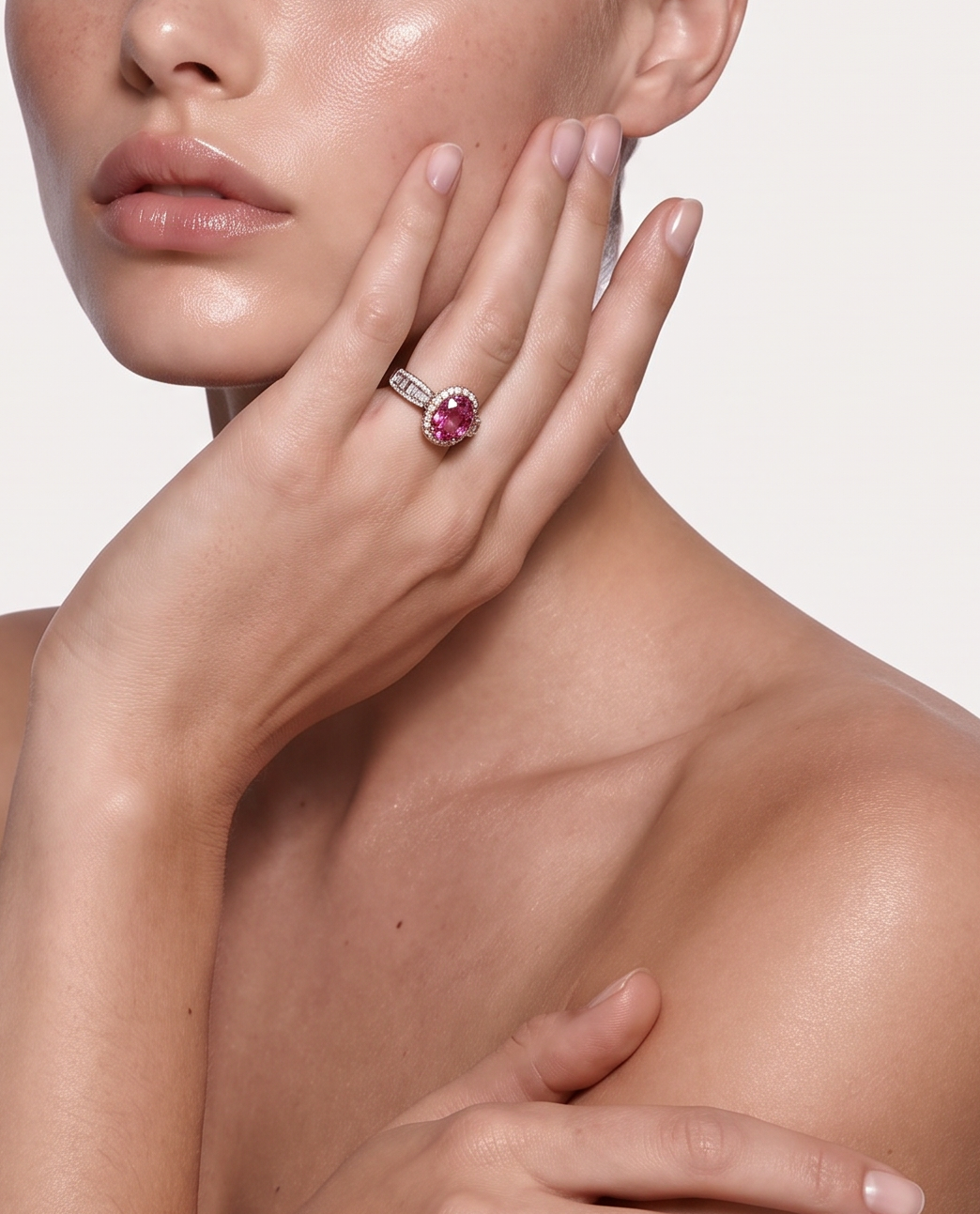 Model wearing the Coral Flame pink topaz halo ring, hand raised to the face