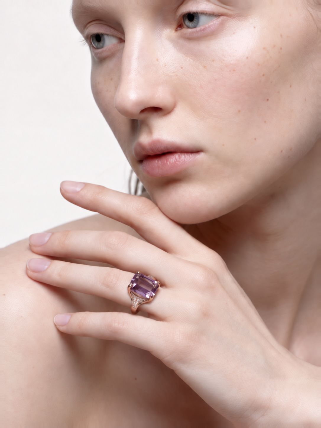 Square amethyst ring worn on the finger, hand resting at the shoulder