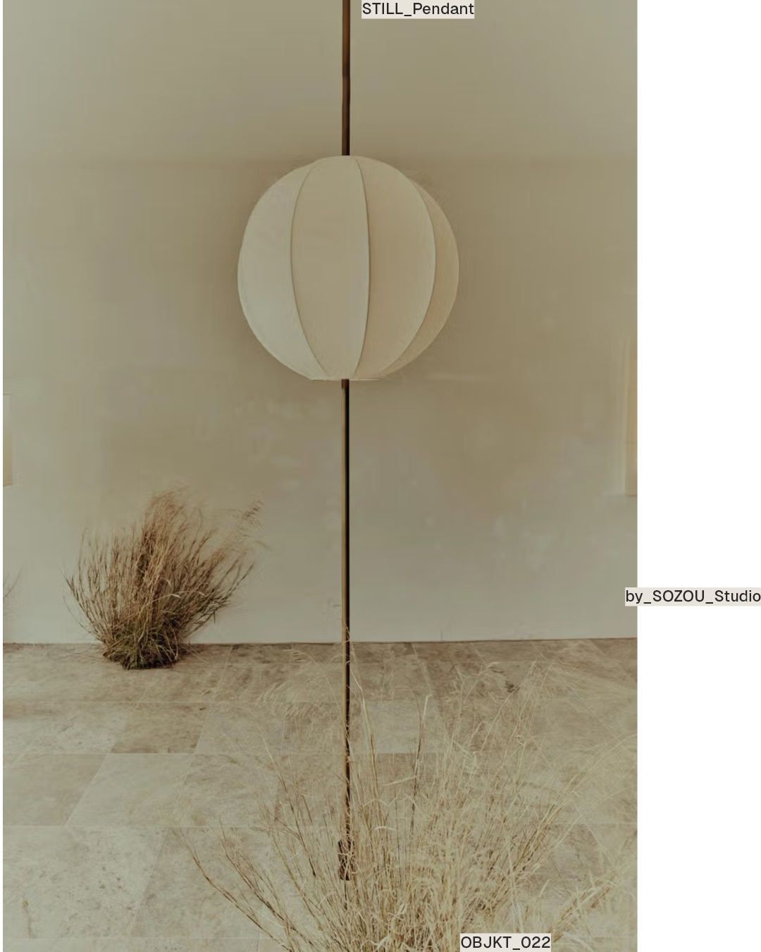 Ribbed spherical pendant on a floor-to-ceiling pole in a beige room with dried grass.