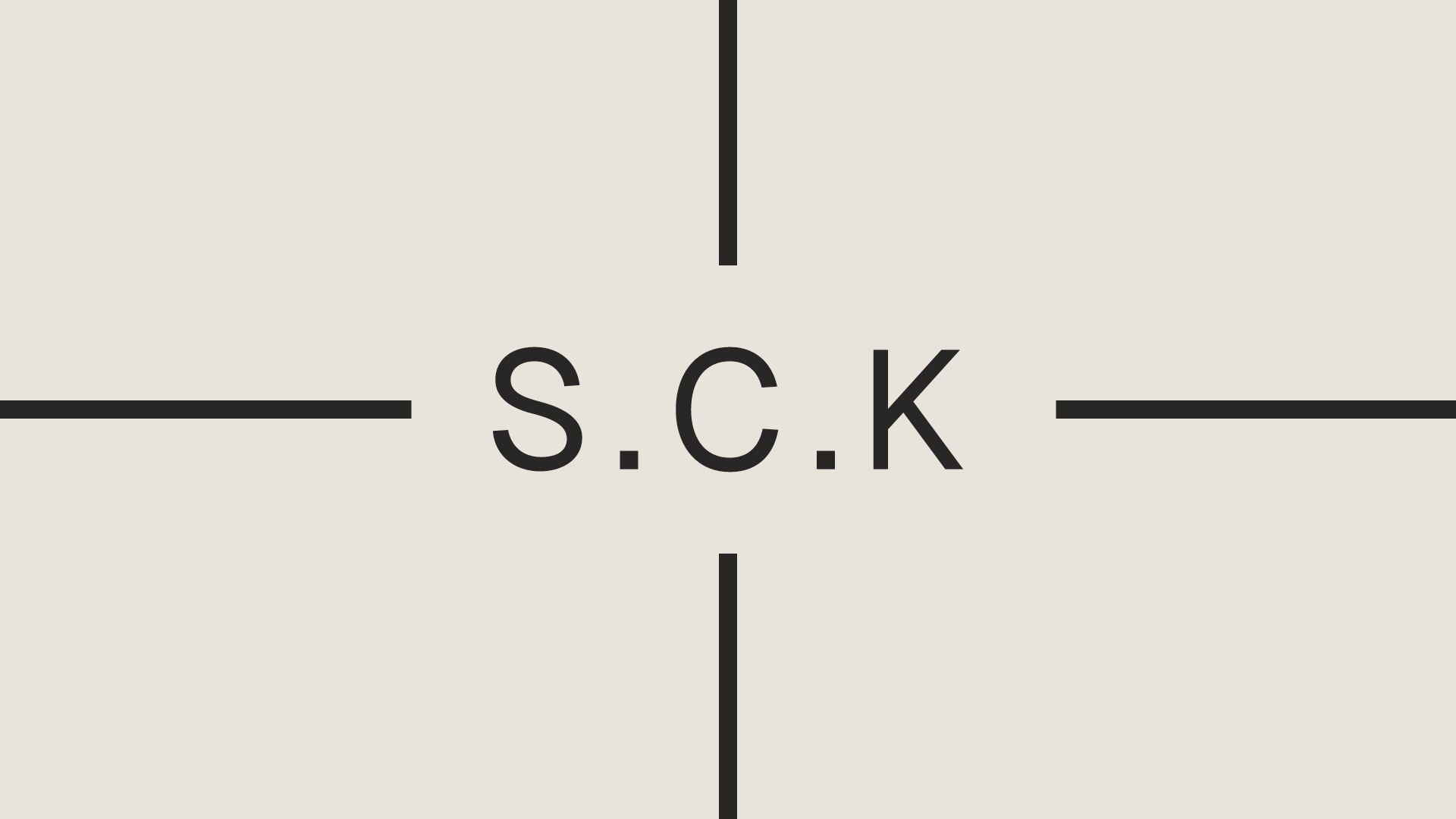 S.C.K in charcoal type with inward crosshair lines on a pale ground.