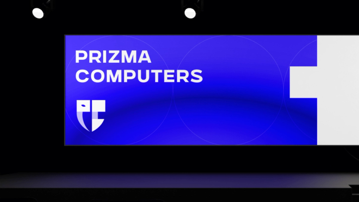 Prizma Computers branding on a large blue stage screen with the shield logo and 'Build your ultimate gaming PC'