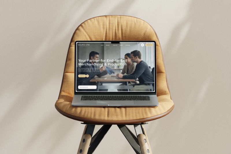 SourceOne Synergies homepage hero, 'Your Partner for End-to-End Merchandising & Production', on a laptop on a chair