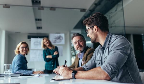Fire kollegaer diskuterer rundt et bord på et møterom. Bilde.