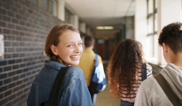 En tenåringsjente går i gangen på skolen med noen venner. Bilde.