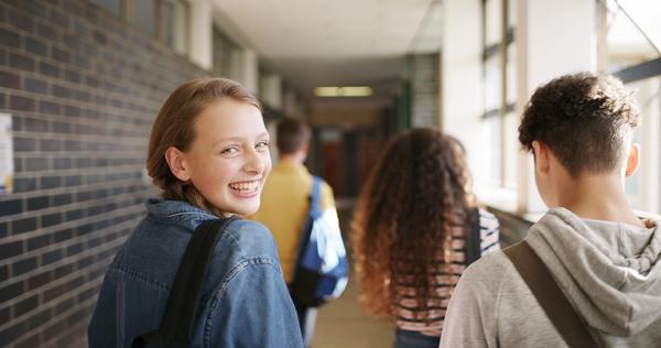 En tenåringsjente går i gangen på skolen med noen venner. Bilde.