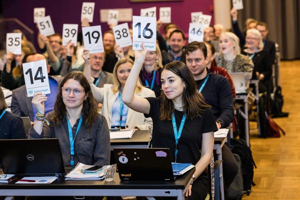 Bilde fra saken på Lektorlagets landsmøte i 2023, delegater som holder opp stemmekort.