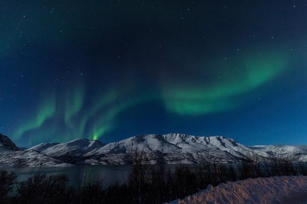 Bilde av grønt nordlys over fjellene ved Alta.