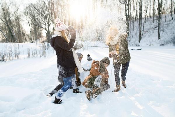 Bilde av en familie som leker i nysnøen.