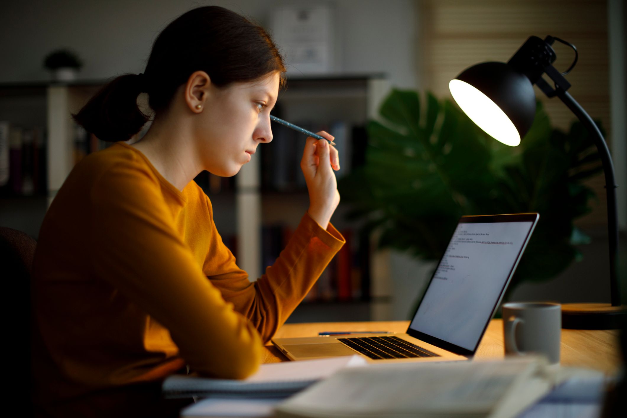 Bilde av en elev som sitter foran laptopen ved et bord og skriver.