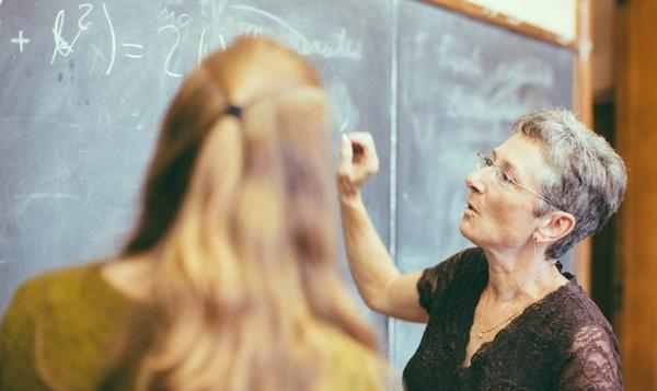 Lærer i et klasserom som skriver på en tavle