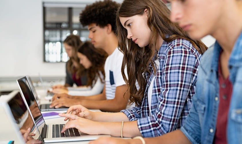 Fem elever sitter ved siden av hverandre og jobber på laptoper. Bilde.