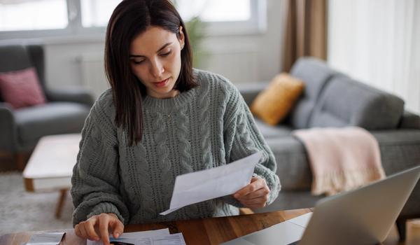 En kvinne sitter og regner på kalkulator. BIlde.