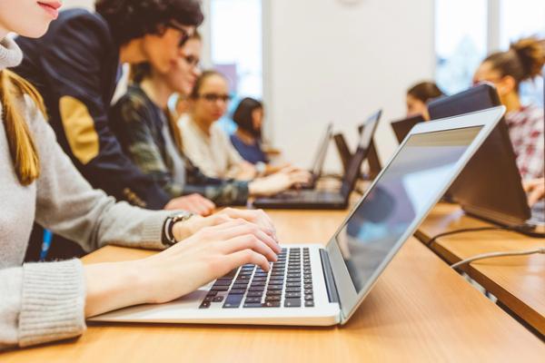 Elever i et klasserom jobber med en oppgave på laptopen.