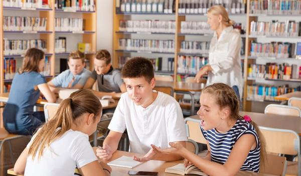 Elever diskuterer rundt et bord i et klasserom. Illustrasjonsfoto.