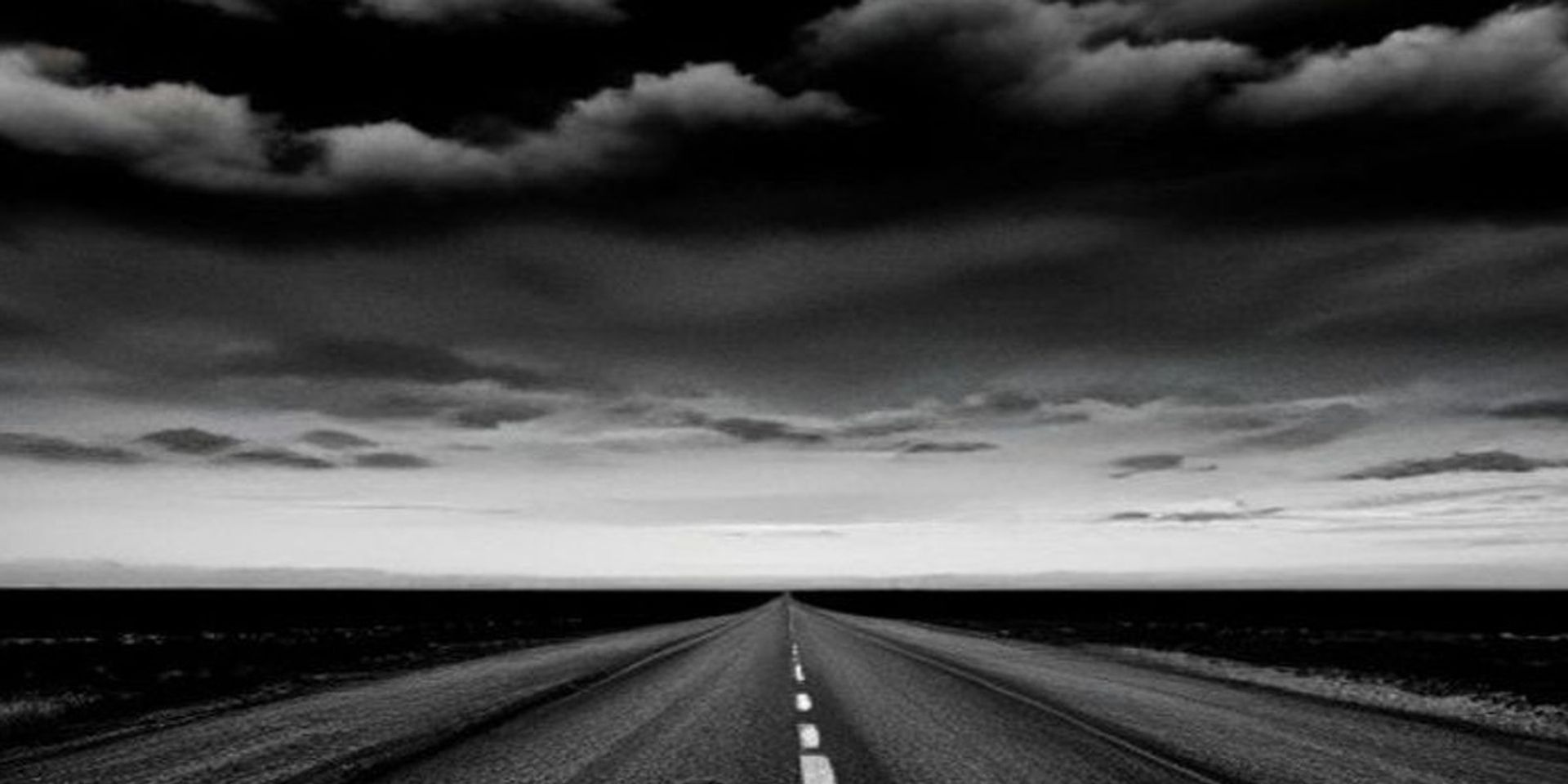 Ruta americana vacía con autos abandonados al costado y cielo amenazante, desolación postapocalíptica
