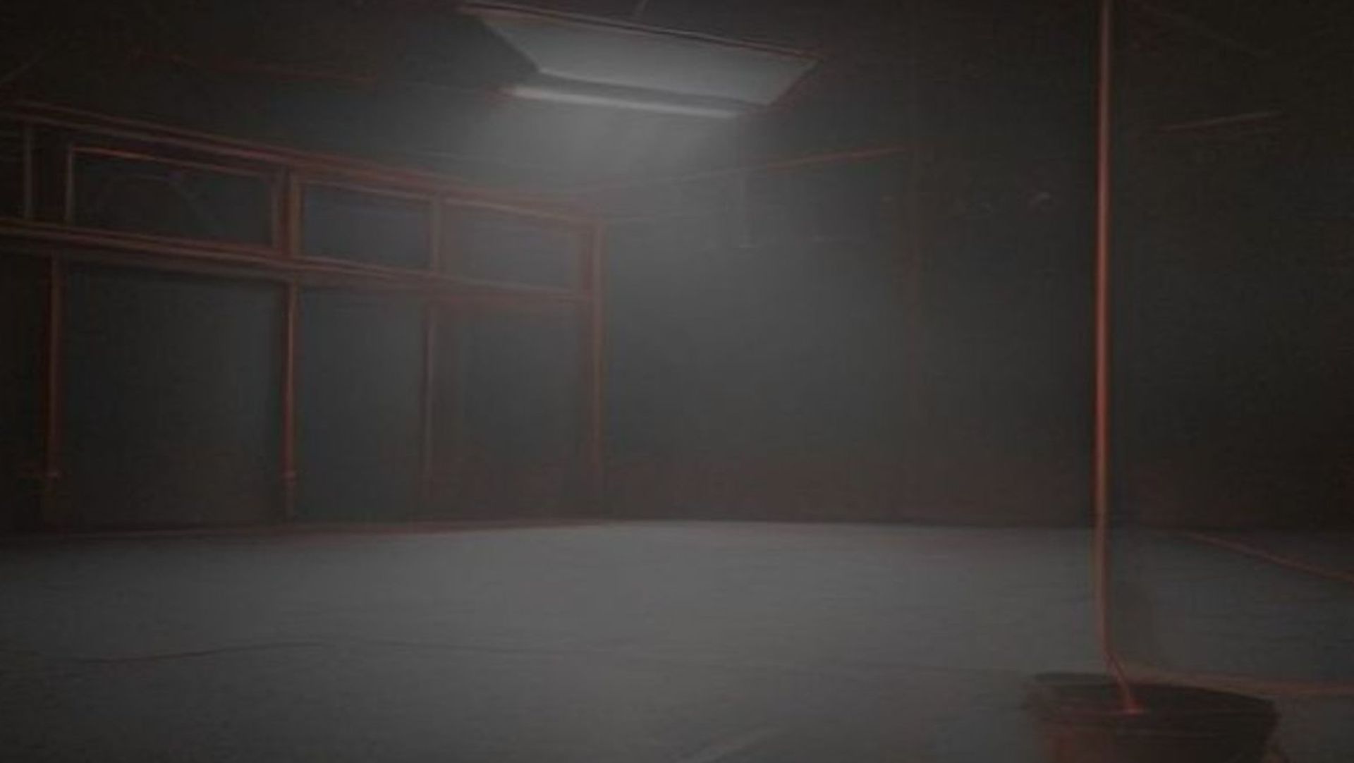 Un gimnasio escolar vacío decorado para un baile de graduación de noche, con un foco de luz y un resplandor rojo ominoso