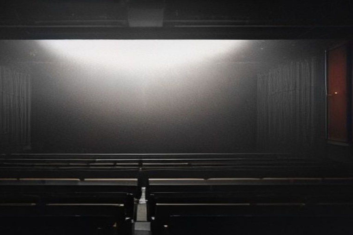 Proyector de cine iluminando una pantalla en una sala oscura, atmósfera cinematográfica