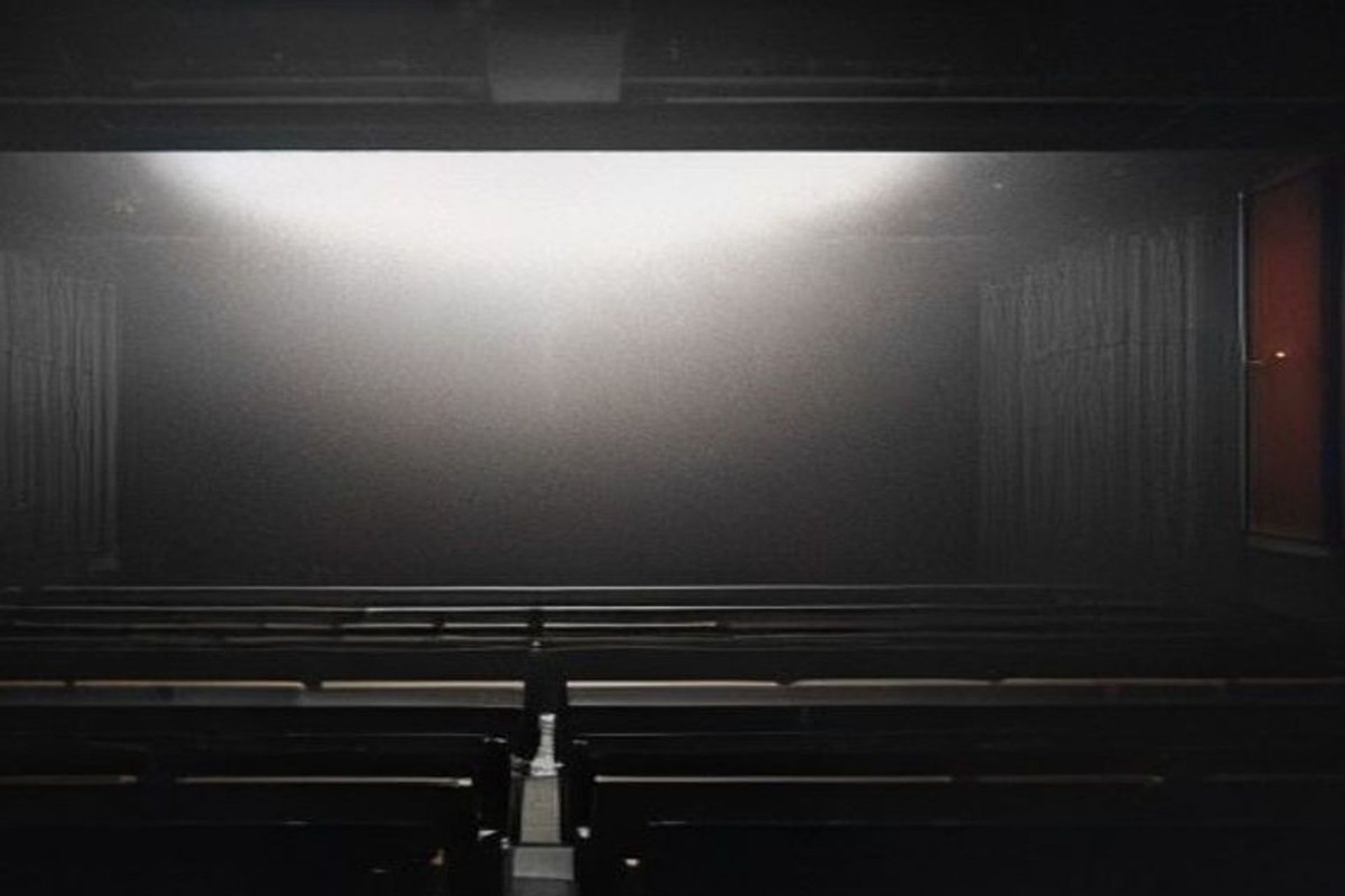 Proyector de cine iluminando una pantalla en una sala oscura, atmósfera cinematográfica