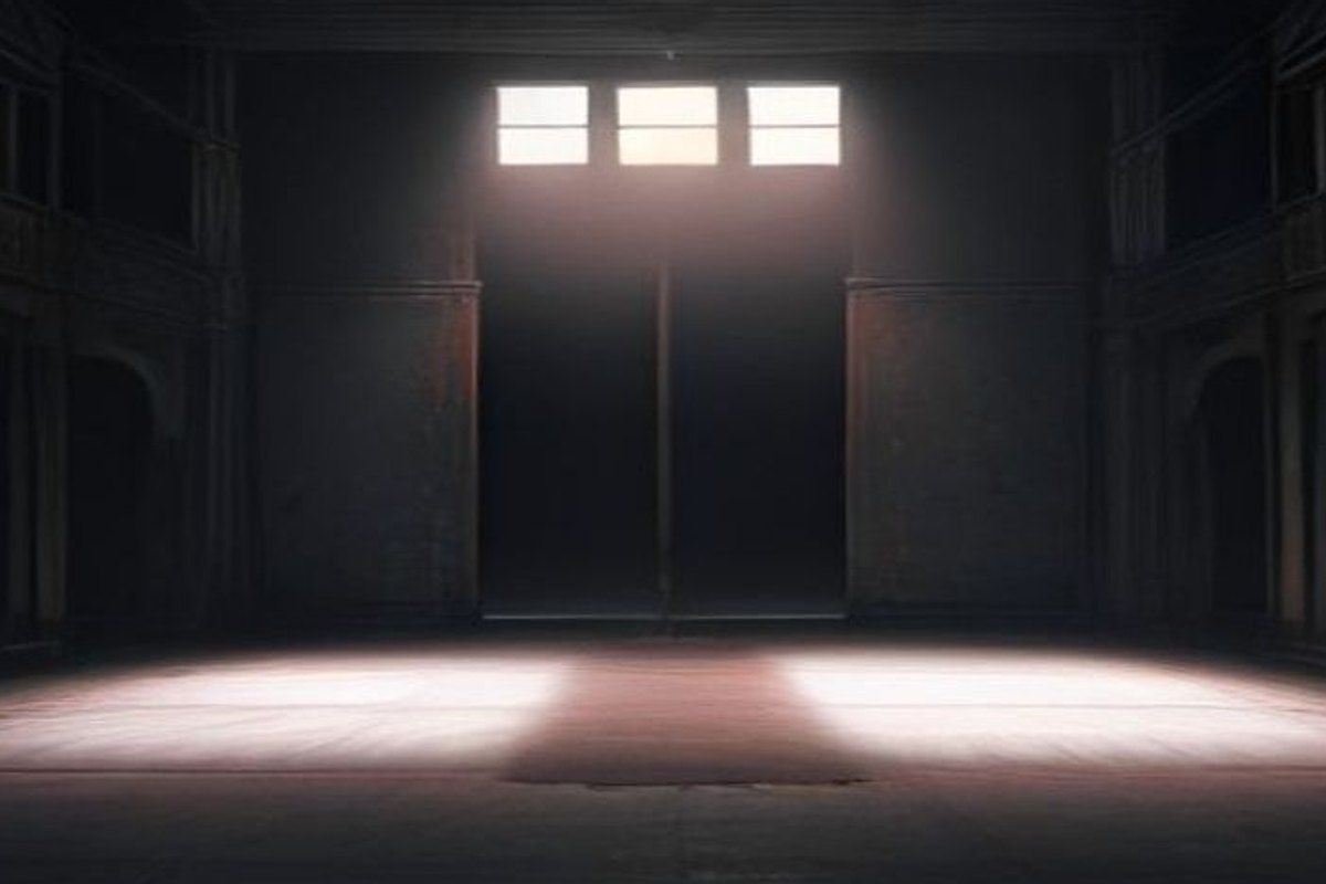 Escenario teatral vacío con un foco iluminando una corona caída sobre las tablas manchadas de rojo