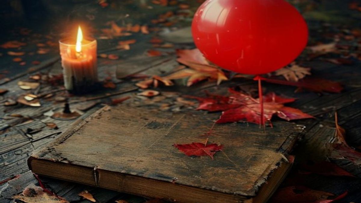 Una novela de terror de tapa dura de los años ochenta sobre una mesa, junto a un globo rojo y hojas de otoño, iluminada por velas