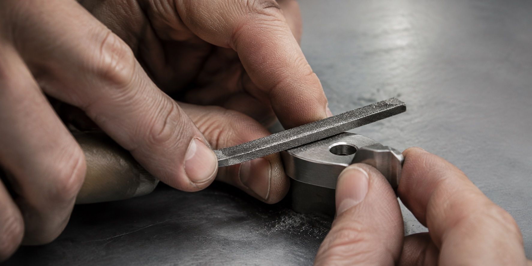 A hand filing a small metal component