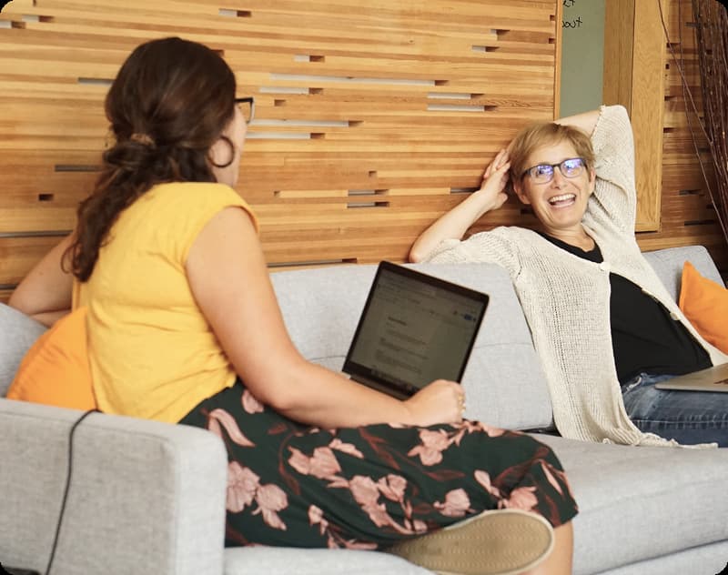 Suzanne smiling, mid-conversation while reclining on a couch