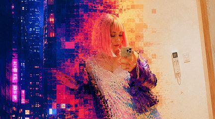 A woman with pink hair taking a mirror selfie with a smartphone, overlaid with a colorful pixelated cityscape effect in pinks, purples, and oranges.