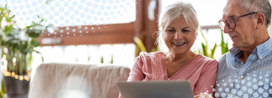 Couple sitting on couch looking at a laptop 