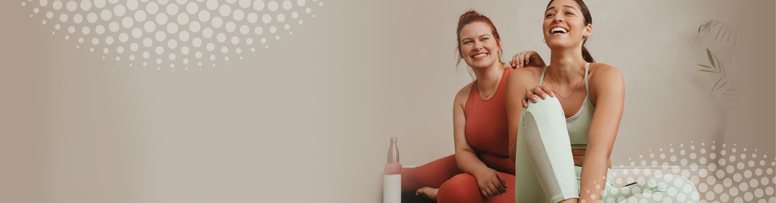 Two women in yoga clothing laughing 