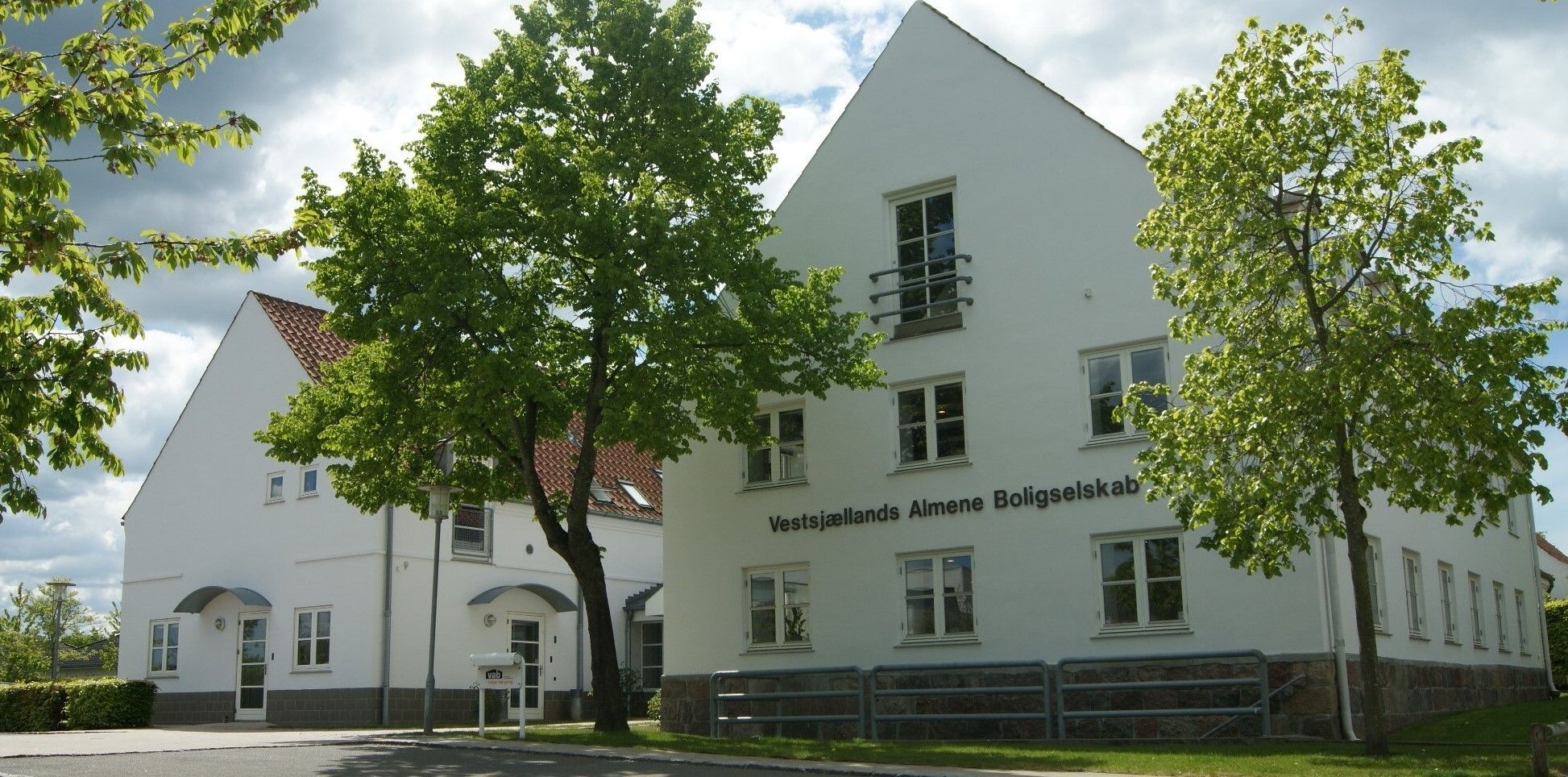 Vestsjællands Almene Boligselskabs hvide kontorbygning bag grønne træer