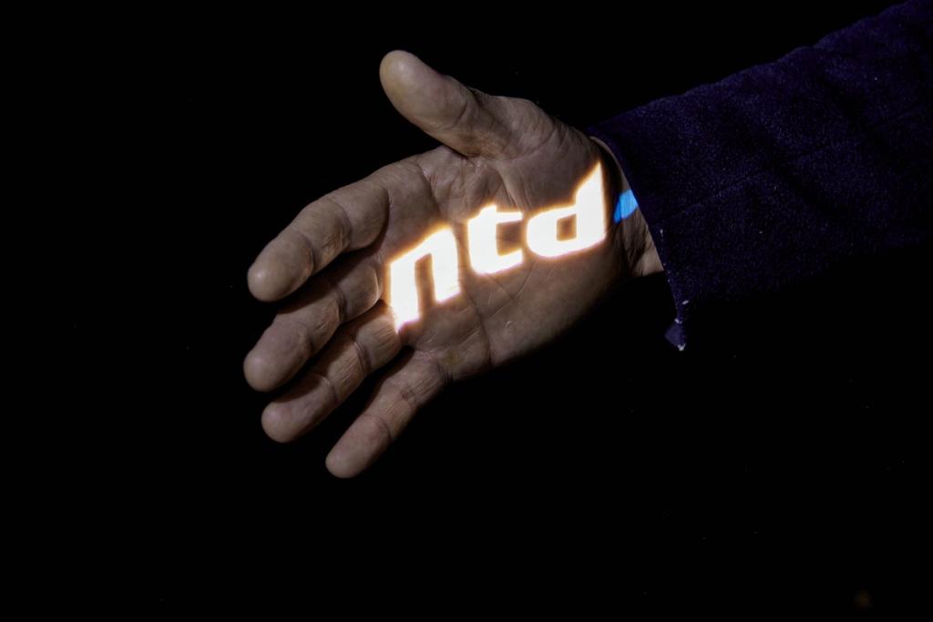 NTD's logo lyser op i en åben hånd mod mørk baggrund