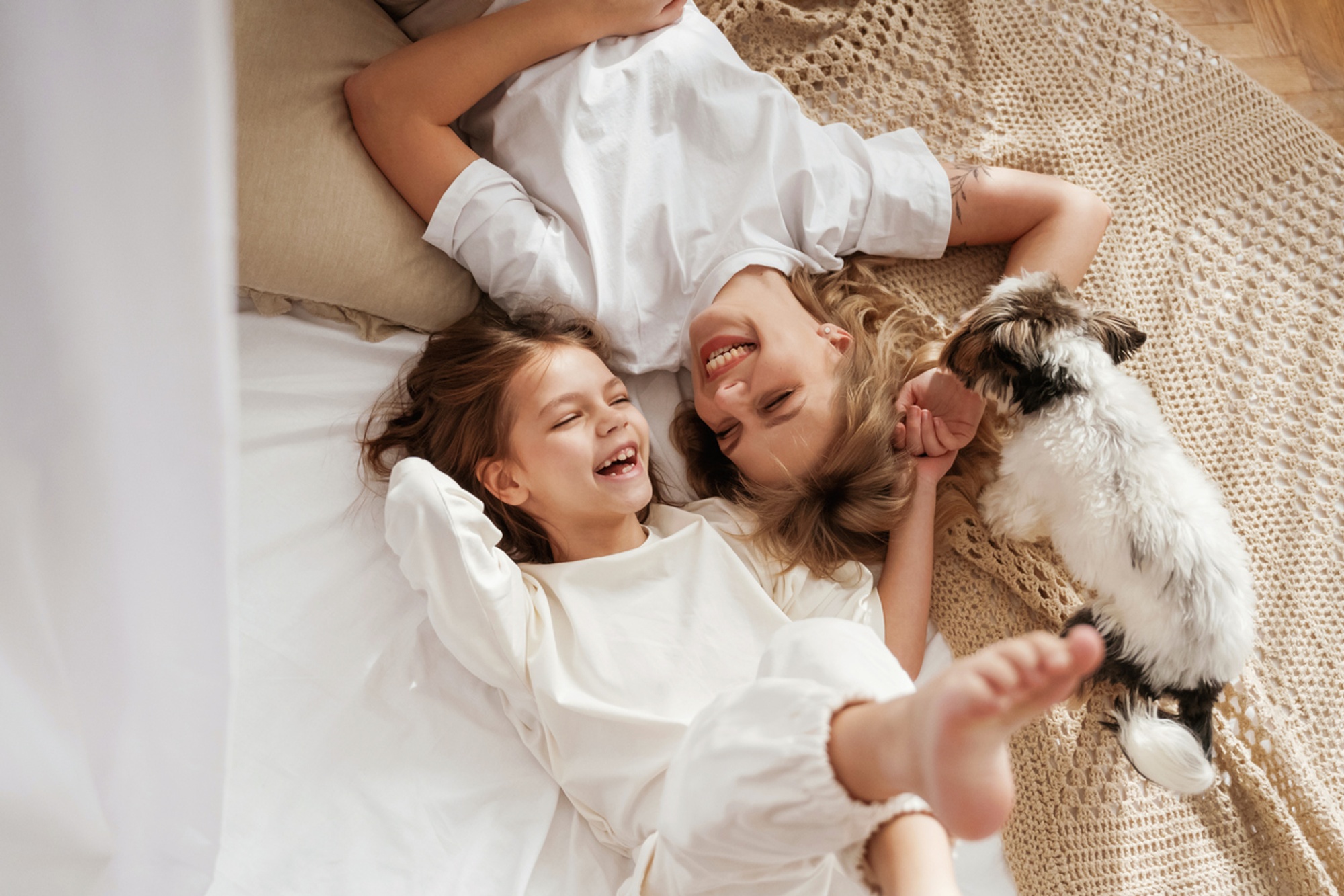 Image of a child, her mother and dog laying down in a sofa looking happy togheter