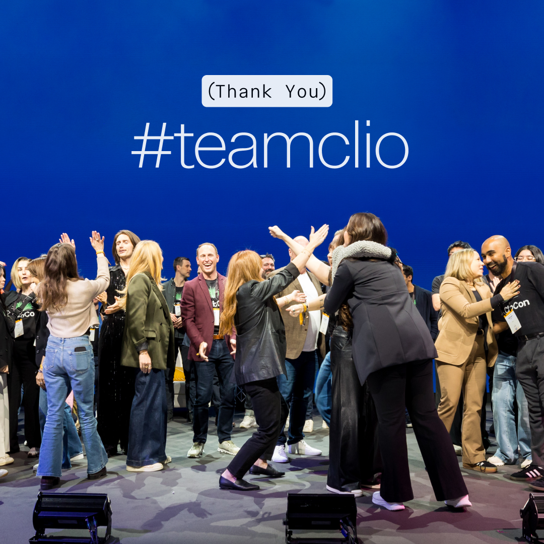 A group of people celebrating on a stage with the text '#teamclio (Thank You)' on a blue background.