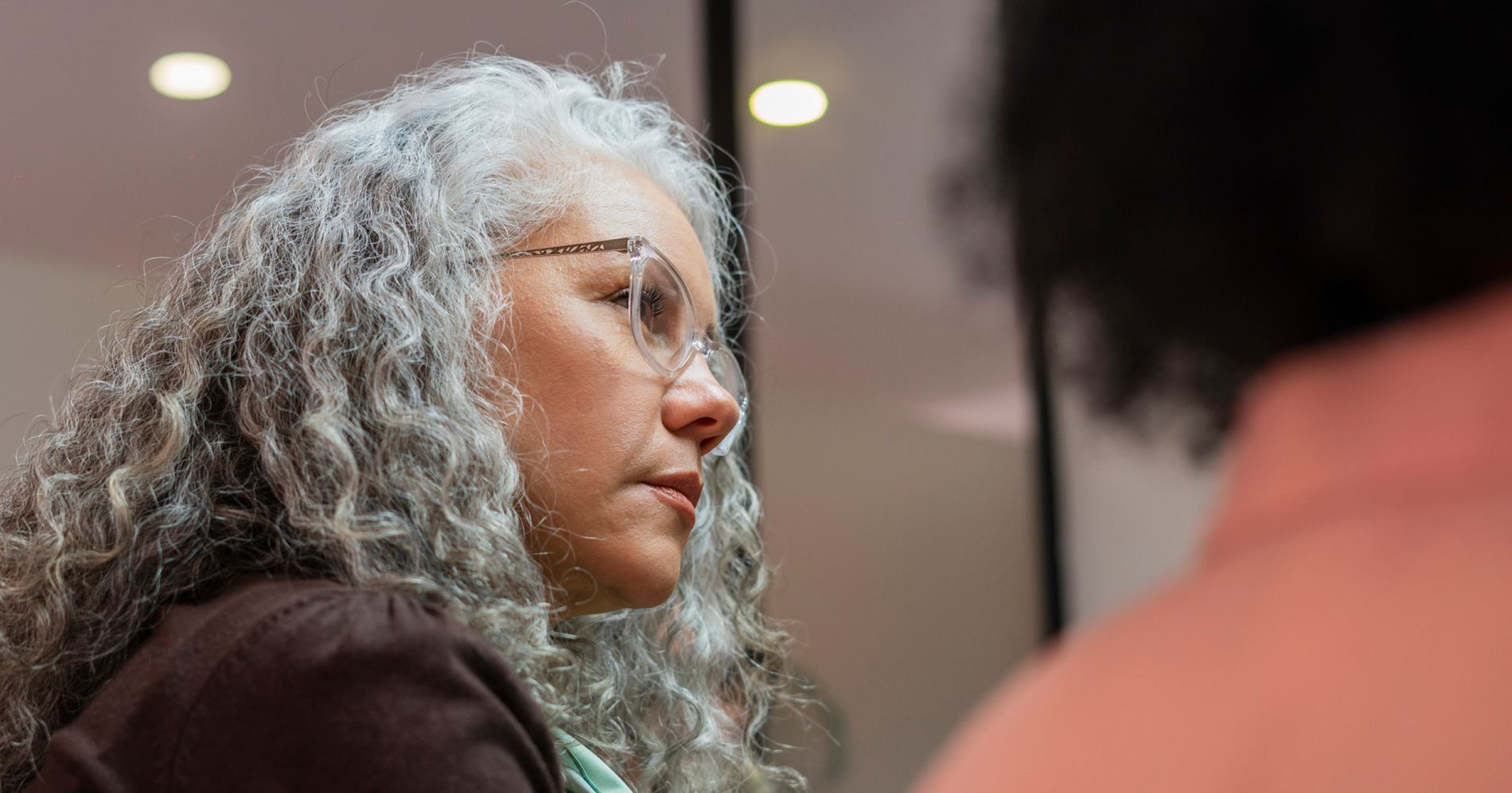 Lawyer with curly gray hair and glasses looking to her right