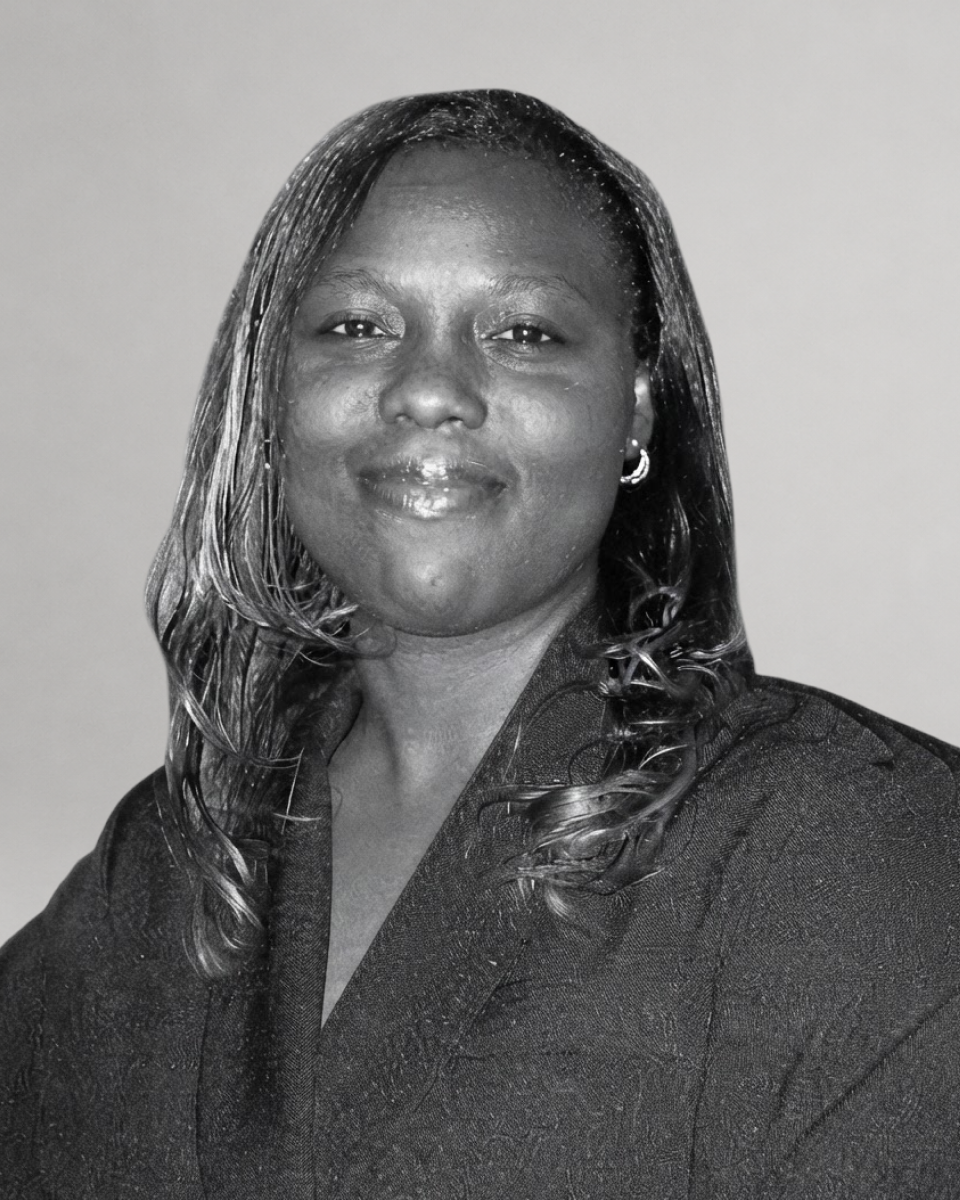 Black and white headshot of a smiling Black woman with long dark hair, wearing a dark jacket.